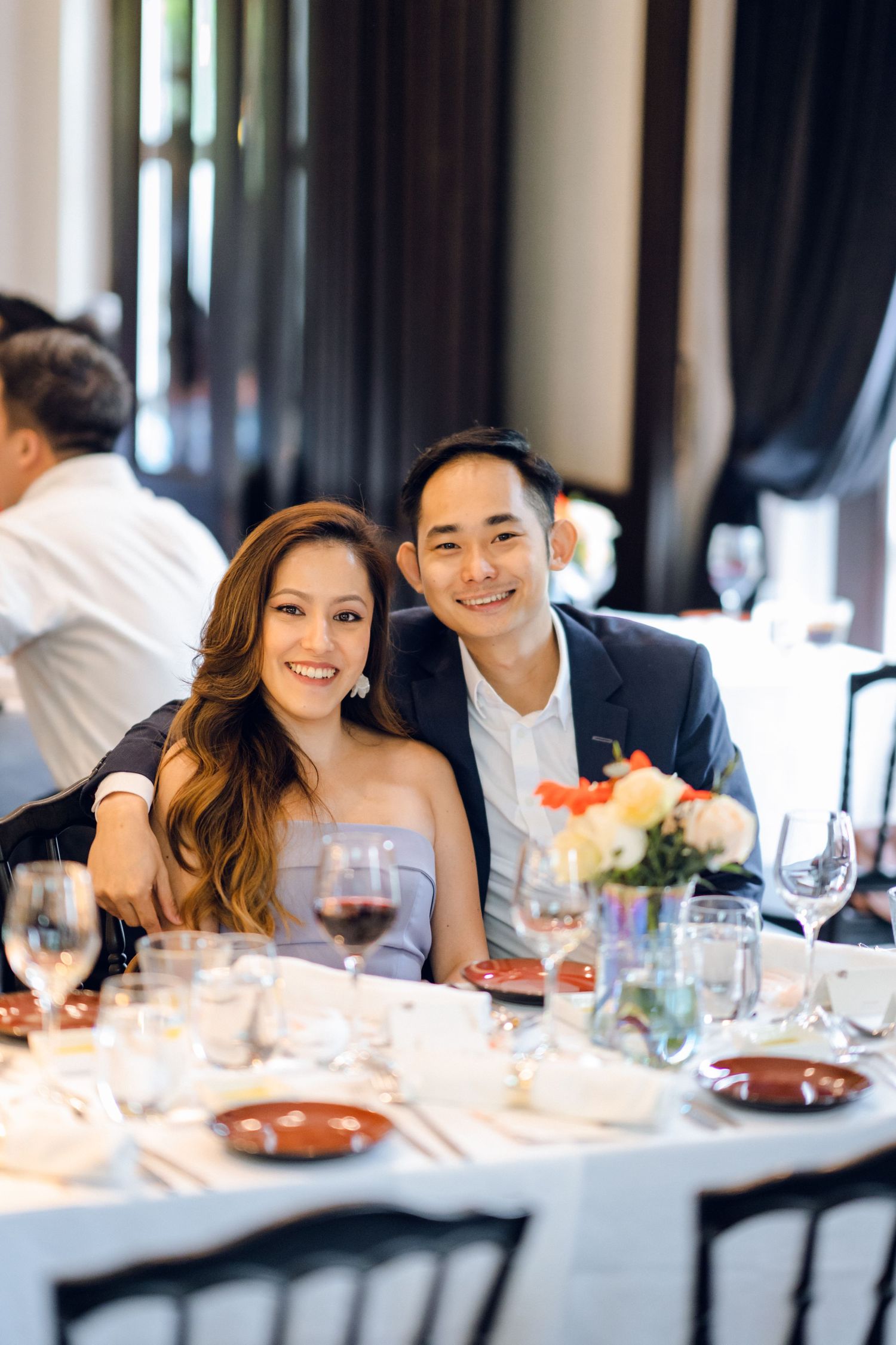 Guests sharing laughter and conversation at an elegant white-tablecloth restaurant setting.