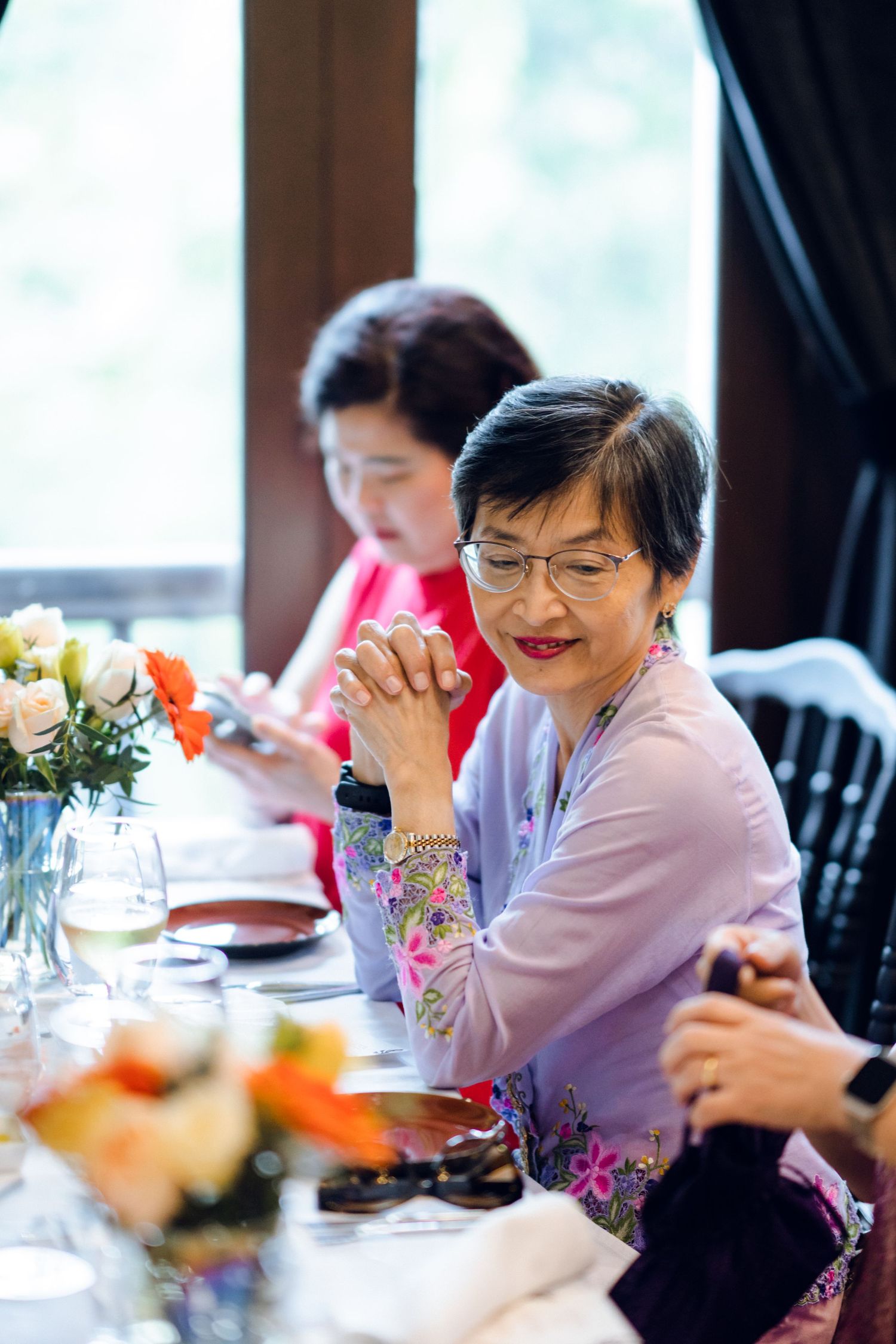 Diners enjoying a festive meal at a bright restaurant with floral decorations.
