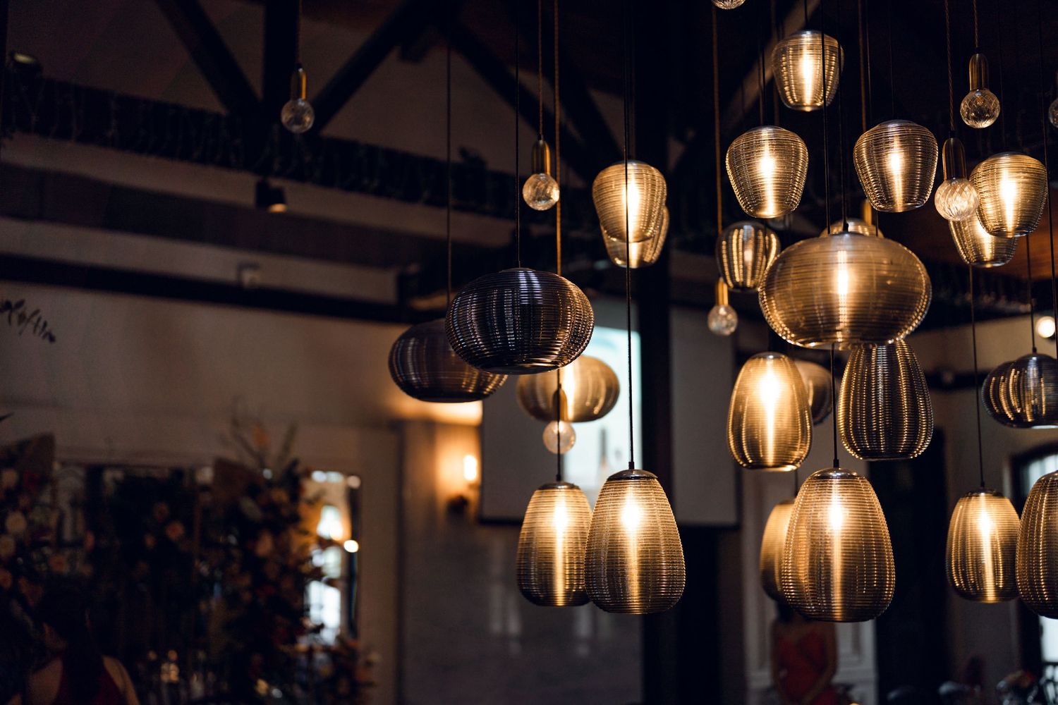 Vintage-style pendant lights hanging from dark wooden beams create warm ambient lighting.
