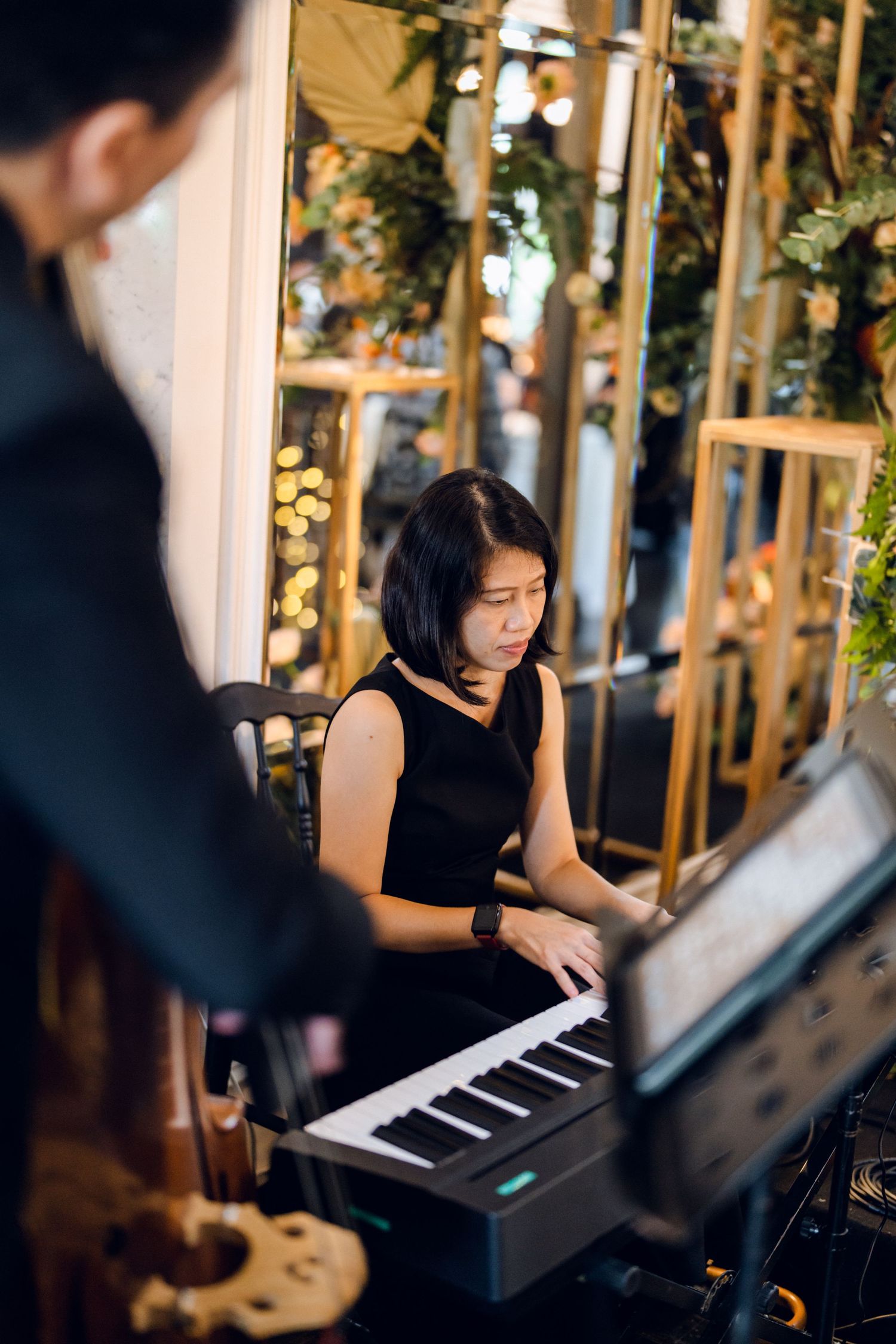 Musician in black attire performs on keyboard during wedding reception.