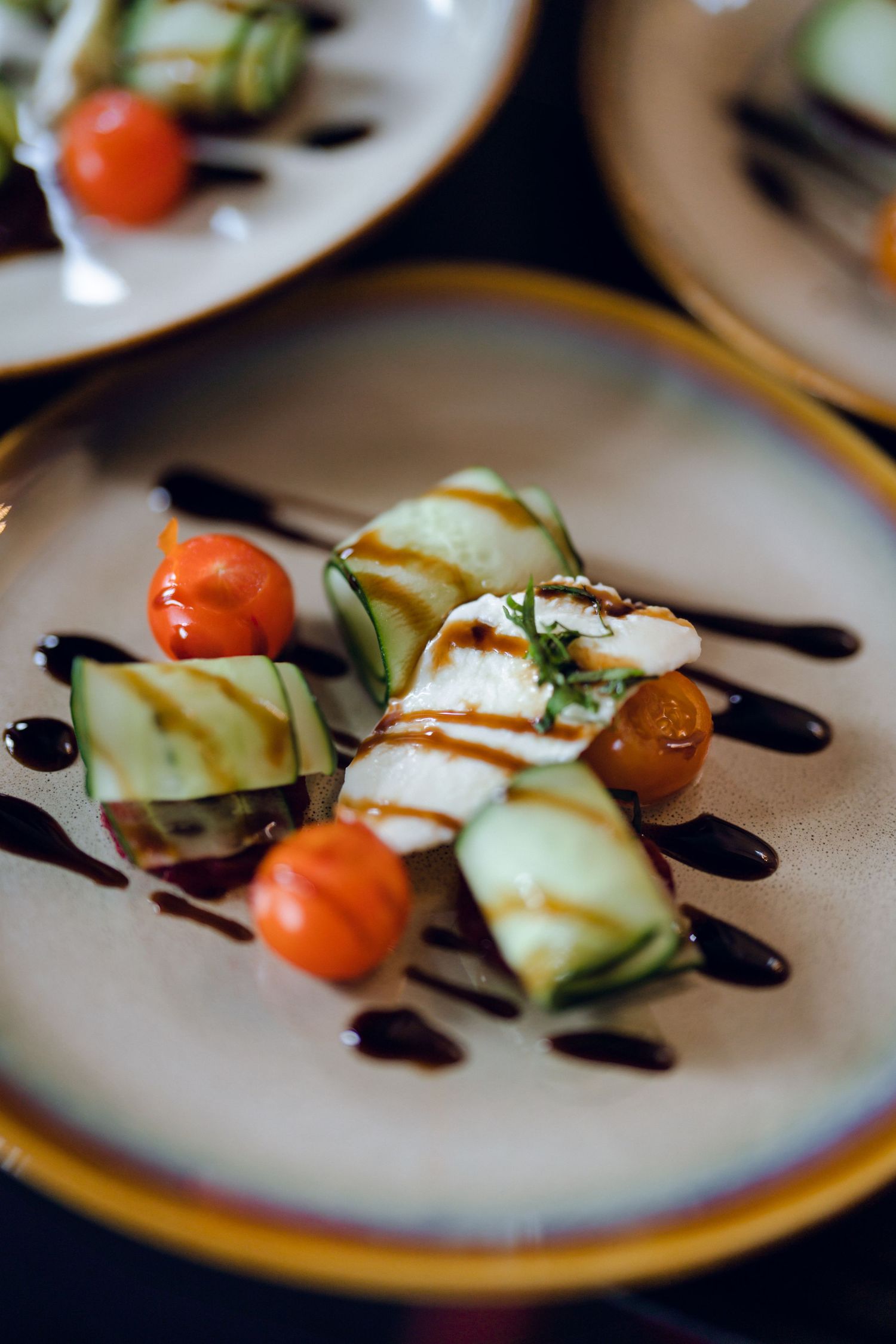 Elegant plated appetizer with cherry tomatoes, cucumber slices and balsamic drizzle.