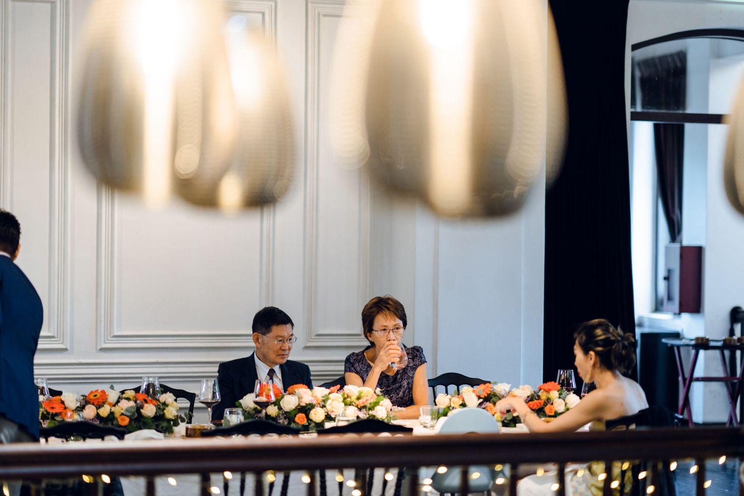 Long reception table setup with white linens and place settings in modern venue.