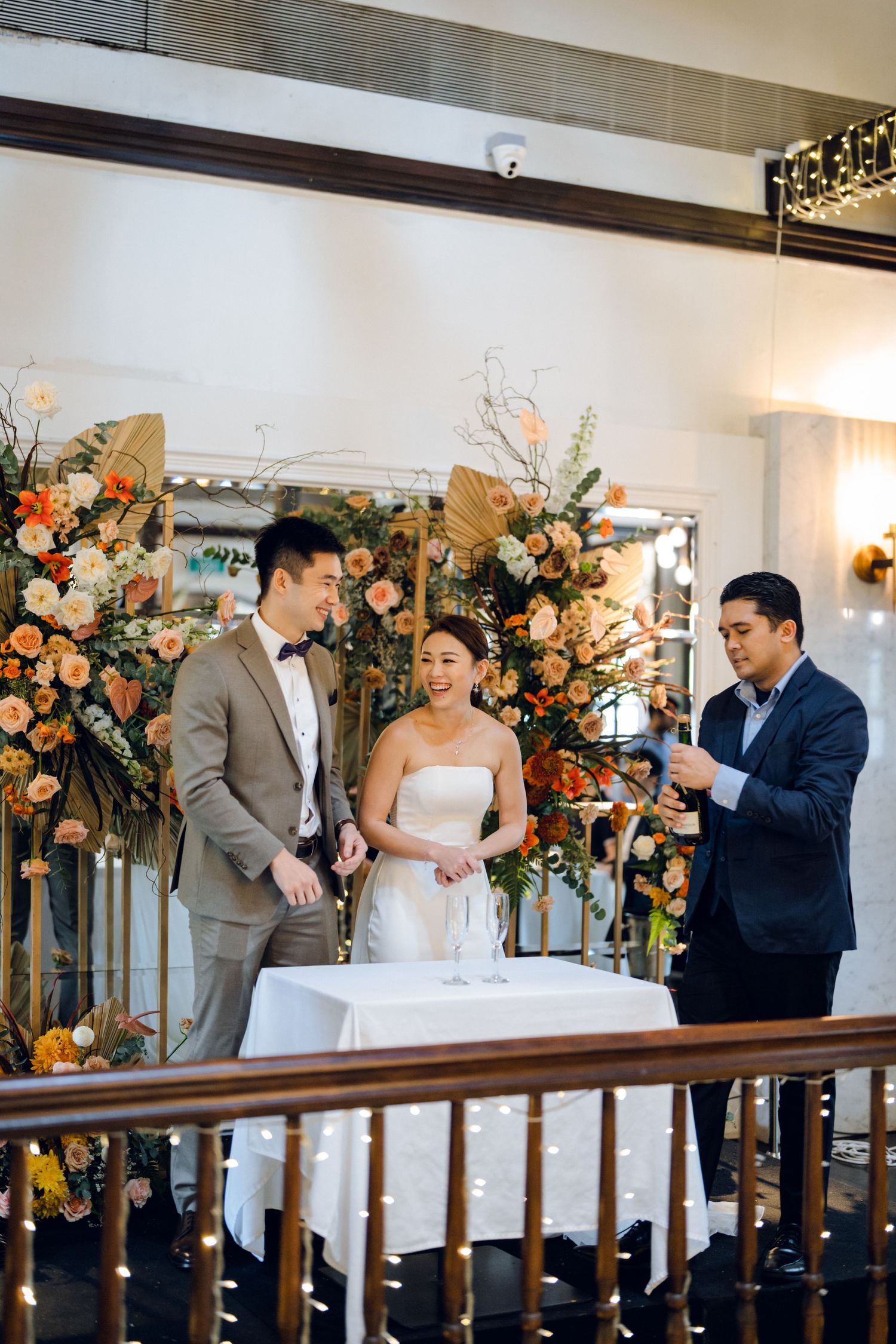 Wedding celebration with floral arrangements and guests toasting in elegant venue.