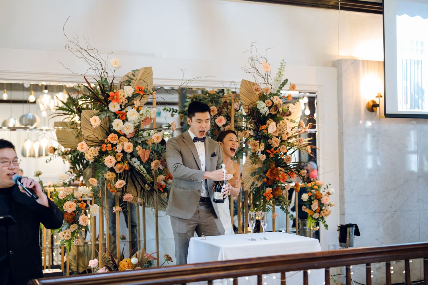 Wedding venue decorated with peach and cream floral arrangements along wooden railing.