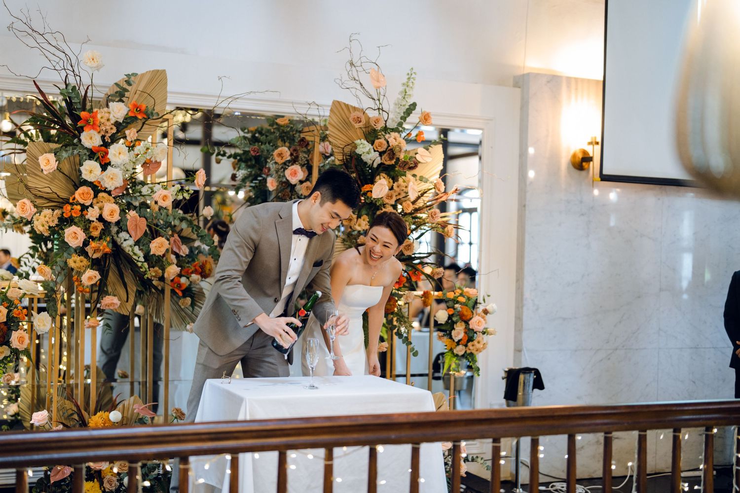 Wedding reception space with elegant floral arrangements and white wall decor.