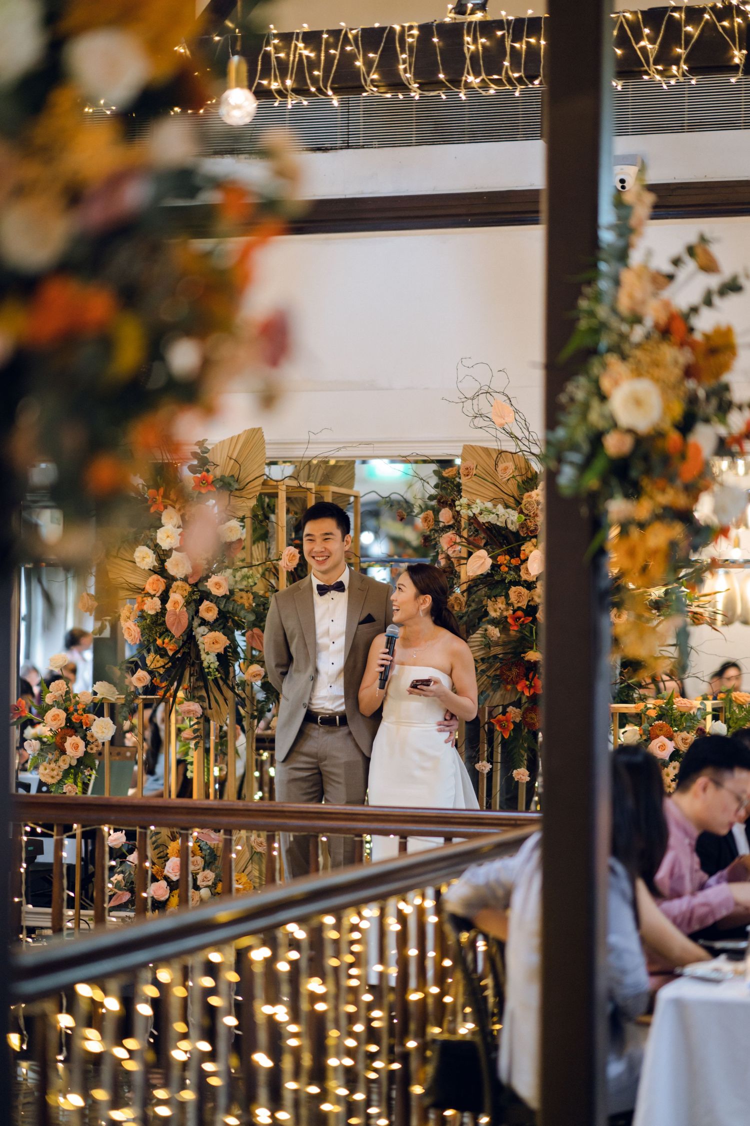 Elegant wedding reception venue decorated with string lights and autumn-colored floral arrangements.