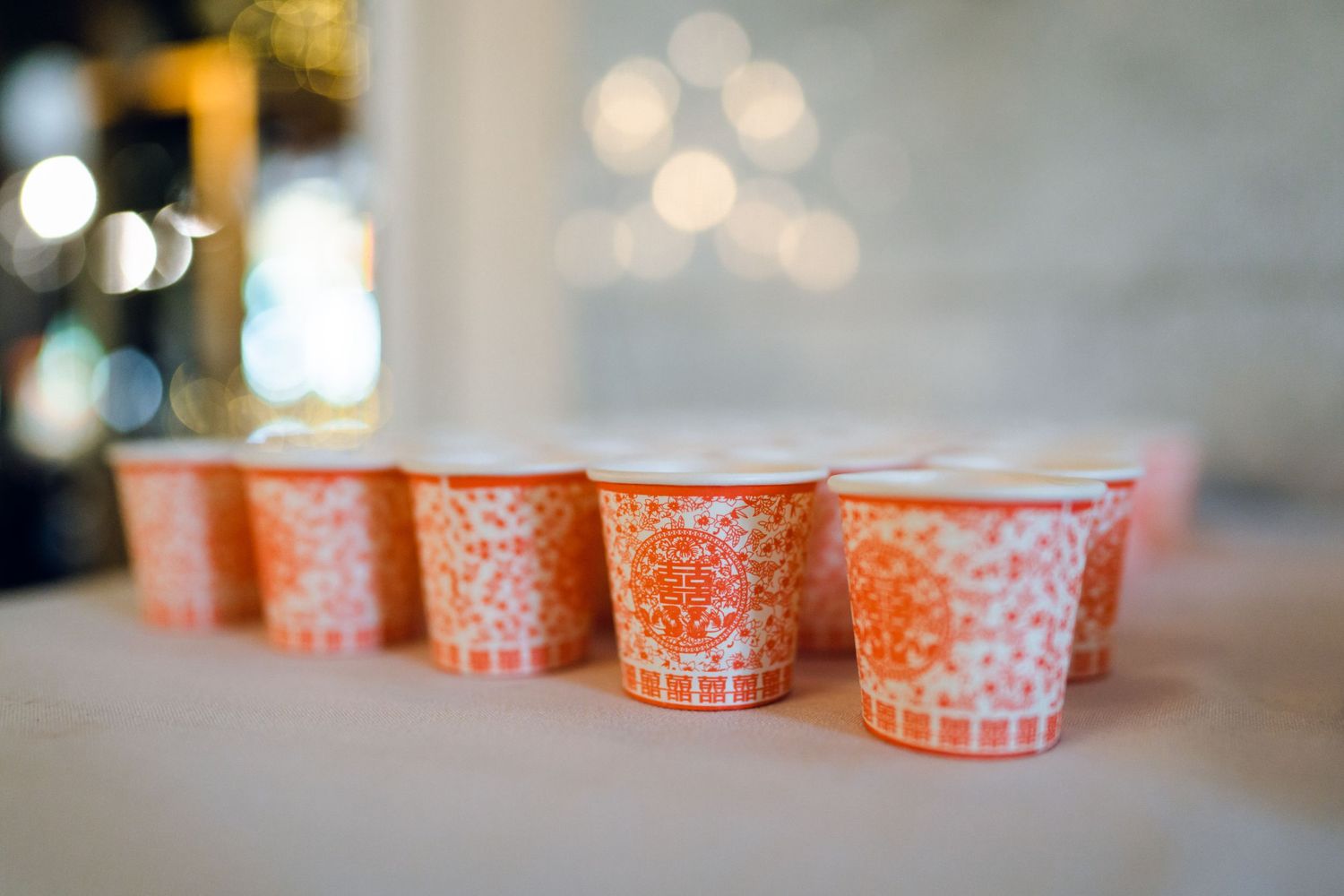 Orange and white patterned paper cups arranged in rows on a light surface.