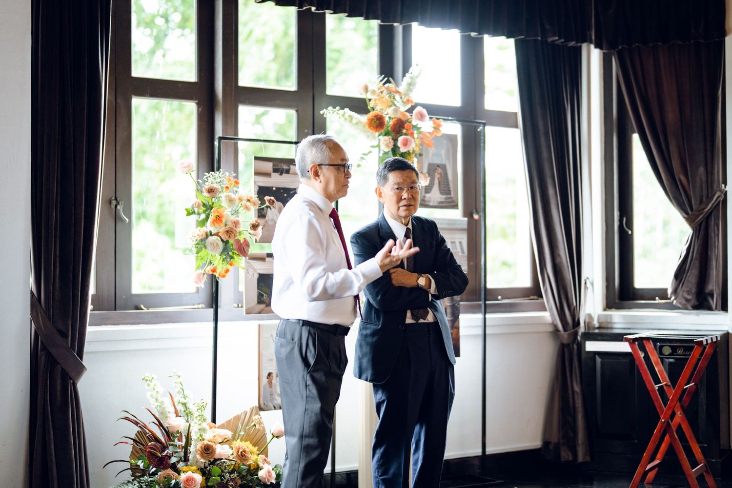 Bright reception venue with large windows, dark curtains, and elegant white walls.