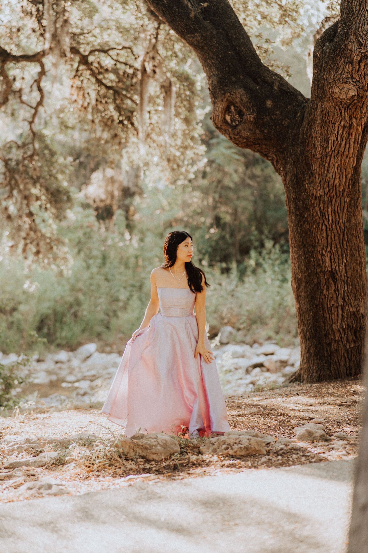 Portrait of a girl in a strapless purple gown looks away from the camera in Pease Park