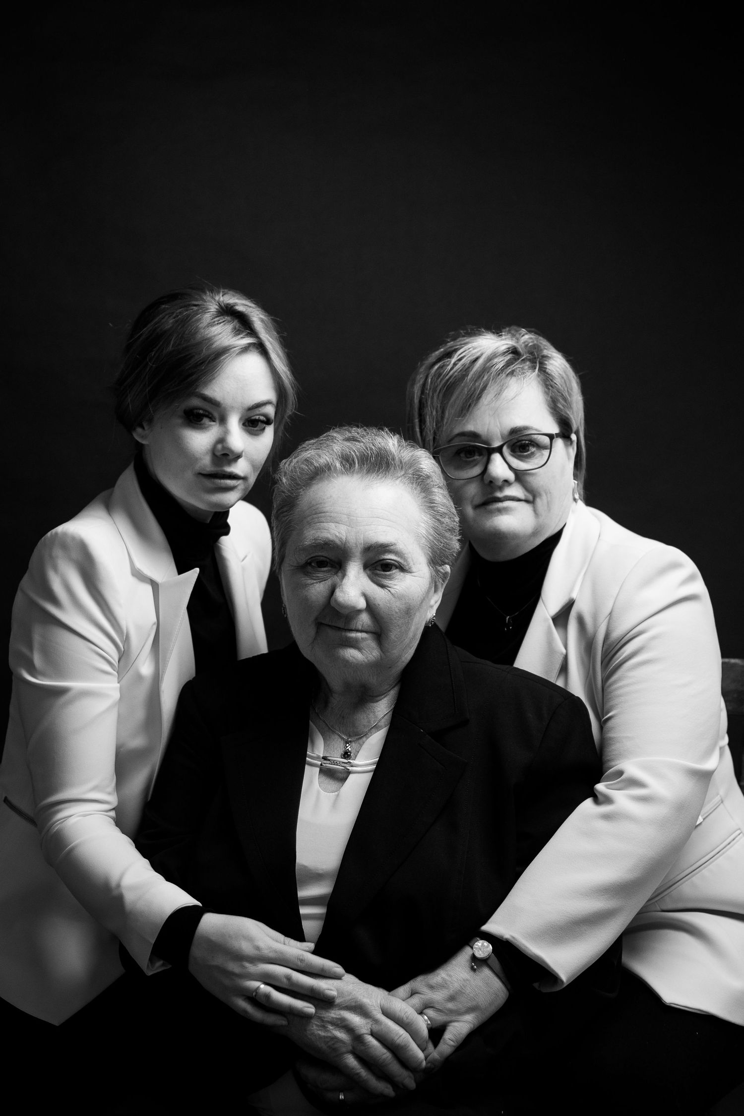 Dramatic black and white portrait of three generations in formal wear.