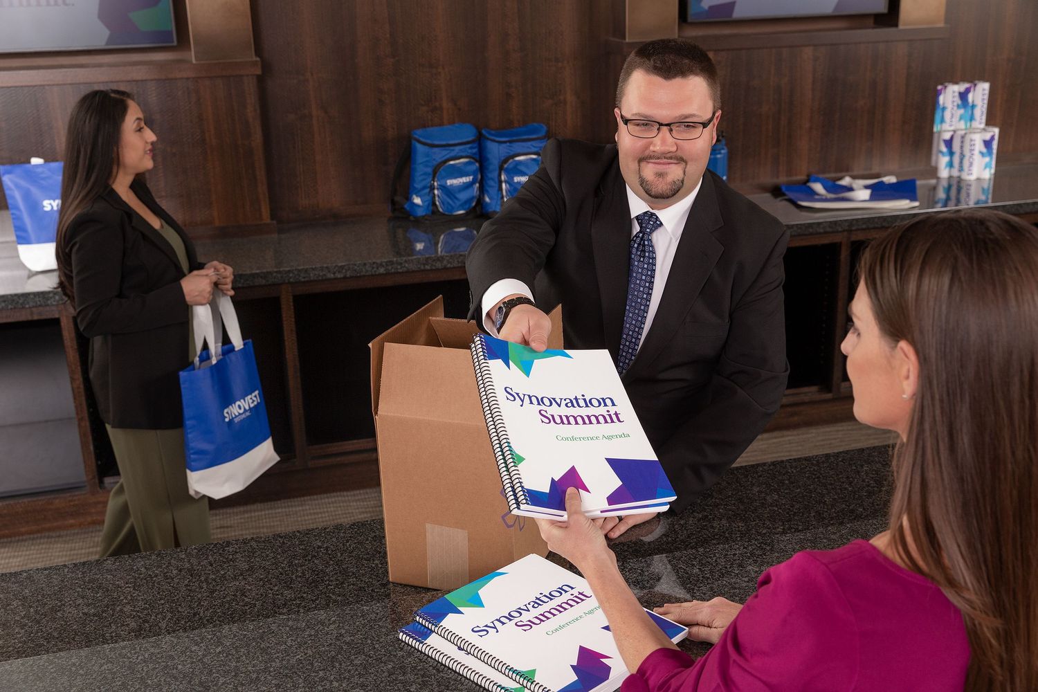 A box of convention booklets printed by FedEx Office are unpackaged in preparation be being distributed at a convention.