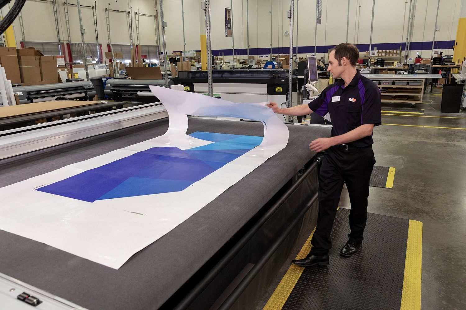 A FedEx Office associate at one of the companies’ Commercial Printing Centers prepares  large graphics for shipping.