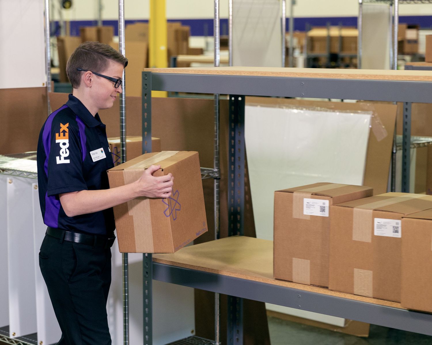 A FedEx Office associate sets a box of convention booklets on a shelf ready to be shipped to the client.