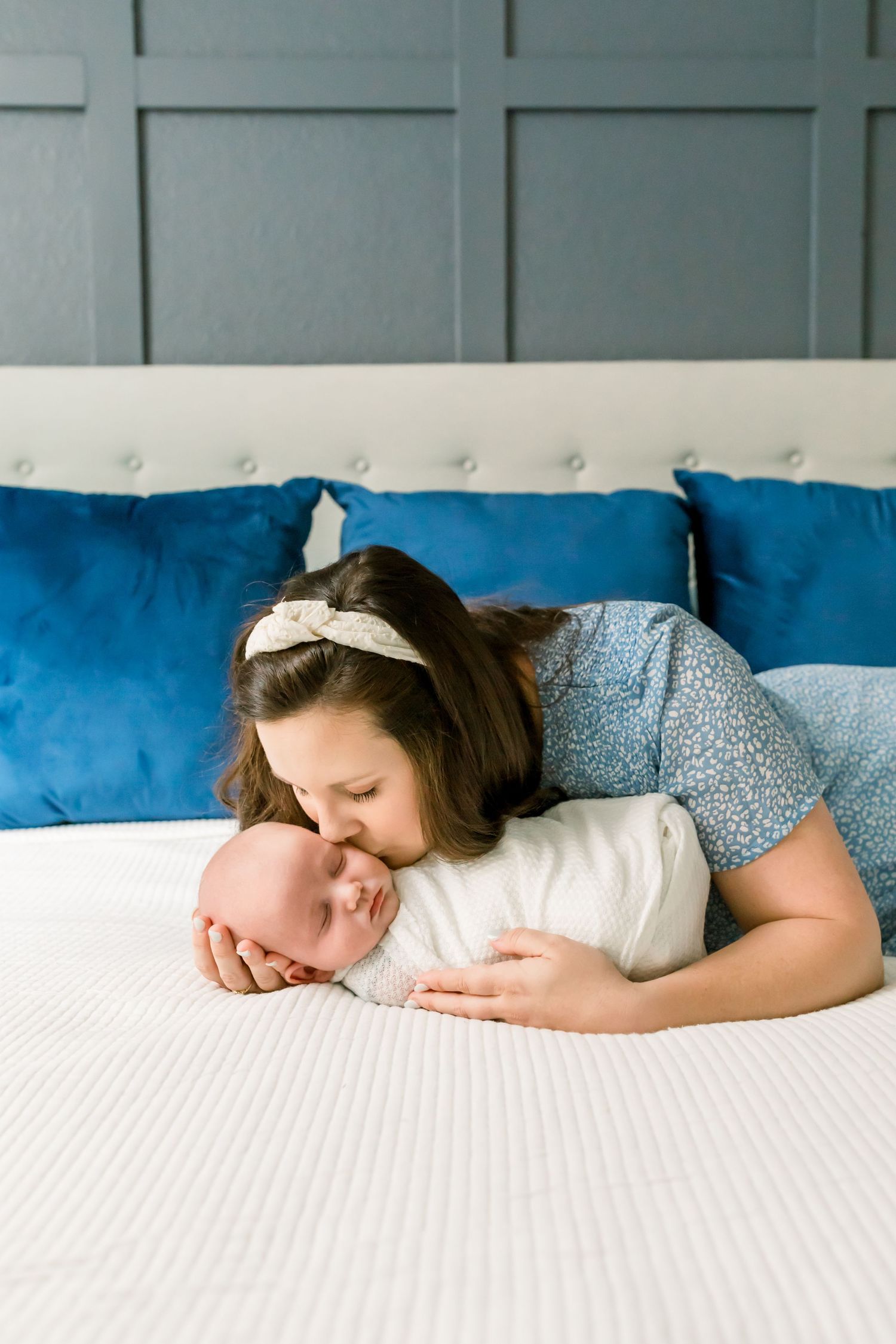 Intimate bonding moment on a white bed with vibrant blue decorative pillows.