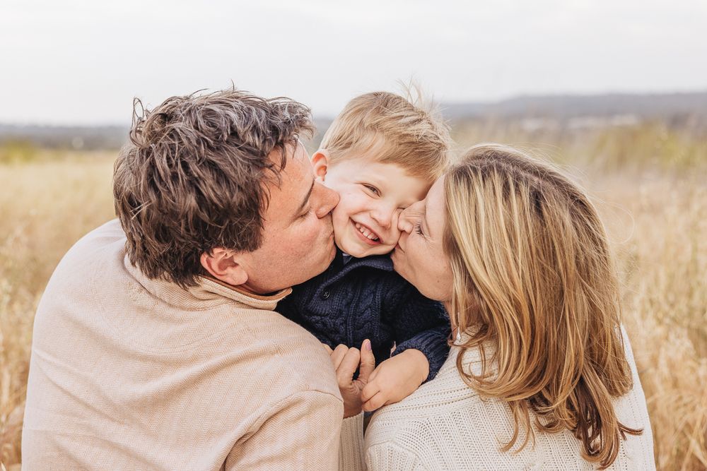 A joyful family moment captured in a sun-lit grassy field.