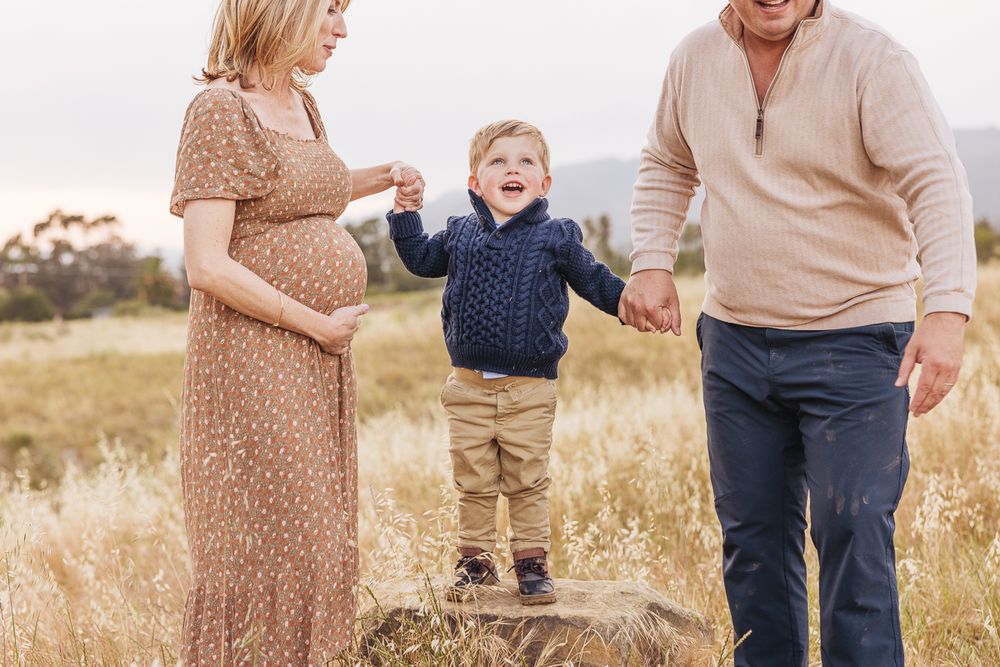 A family enjoying time together in a sunlit field with mountains visible in the distance.