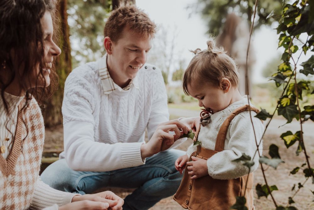 Casual outdoor family interaction while sitting together on ground near garden arch.