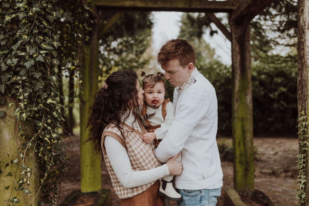 A family shares an intimate moment together under an ivy-covered pergola.