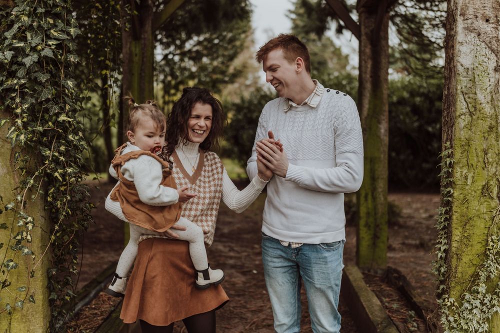 Candid family interaction beneath moss-covered garden archway during outdoor photo session.