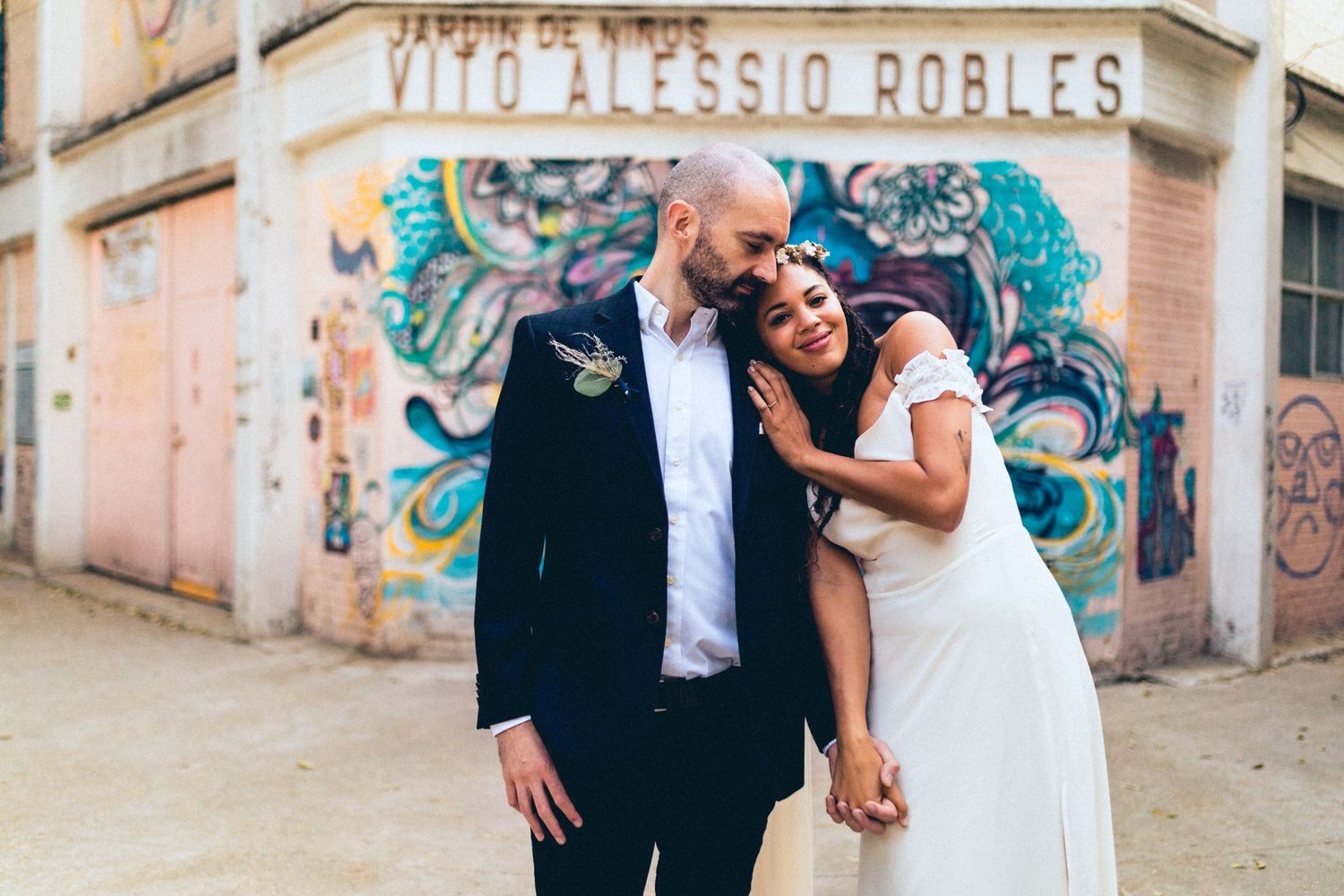 Candid wedding photo of a couple laughing together against a colorful graffiti wall.
