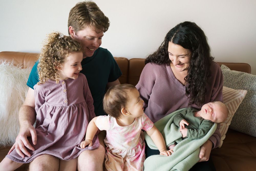 Family gathered together on couch for candid lifestyle portrait in soft natural light at home.