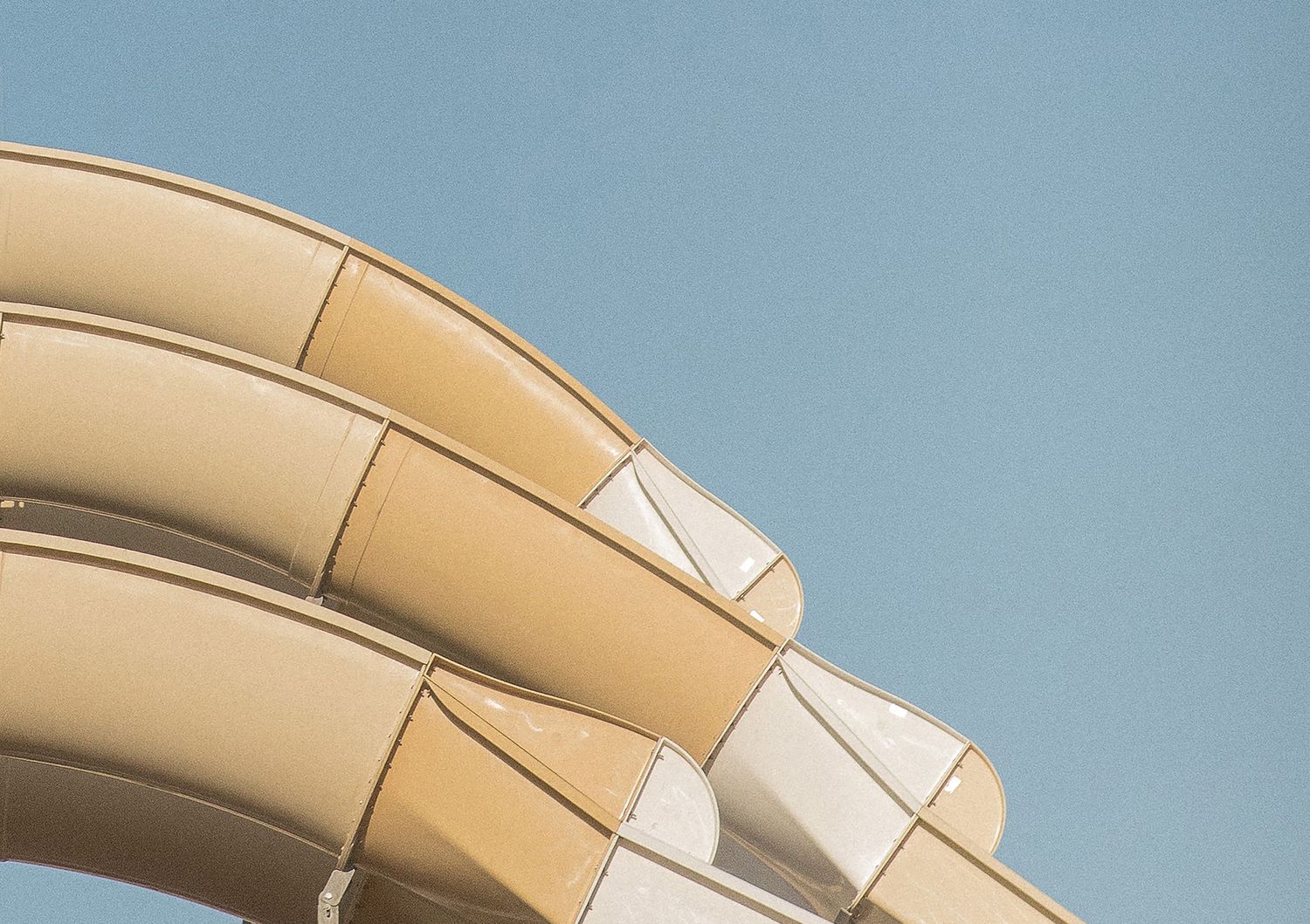 Modern curved architectural detail of a beige building facade against blue sky.