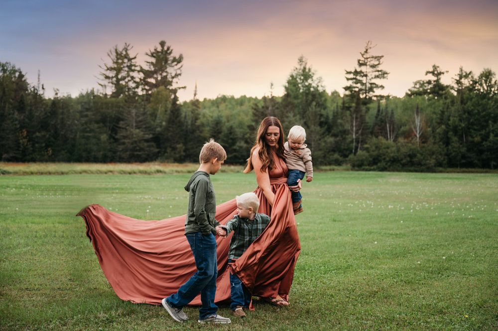 Woman in dramatic dress posing with sons in field in Orr, Minnesota.
