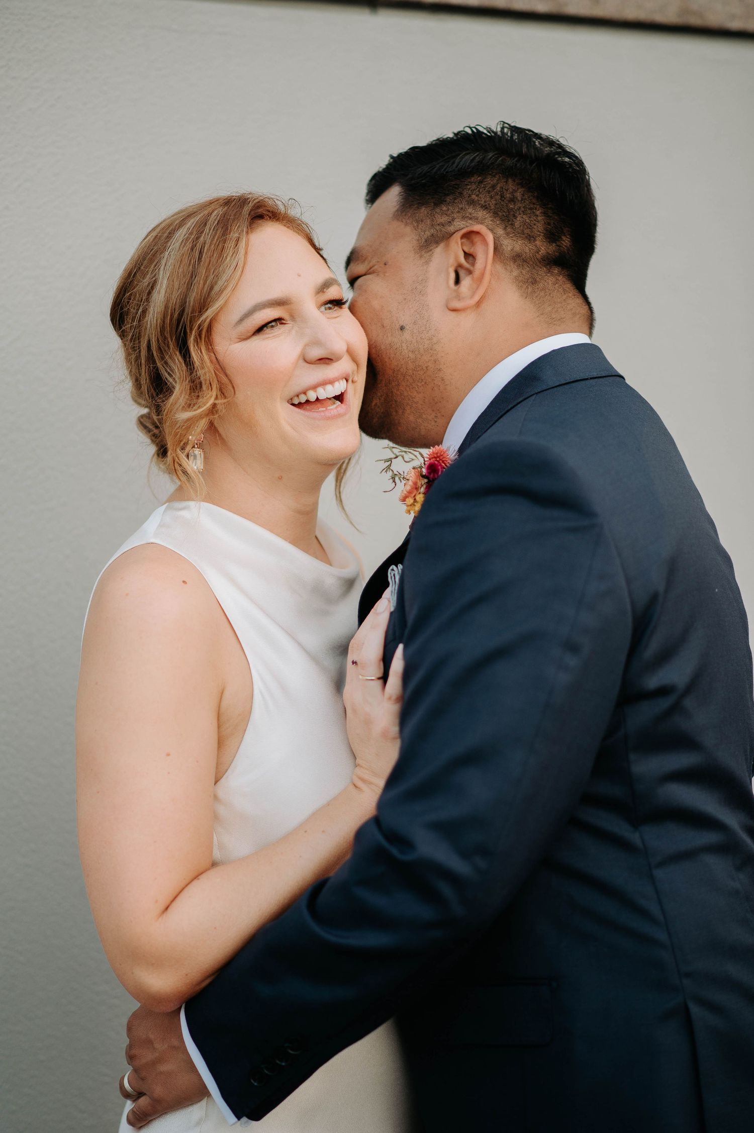 A joyful couple shares an intimate laughing moment during their wedding portraits.