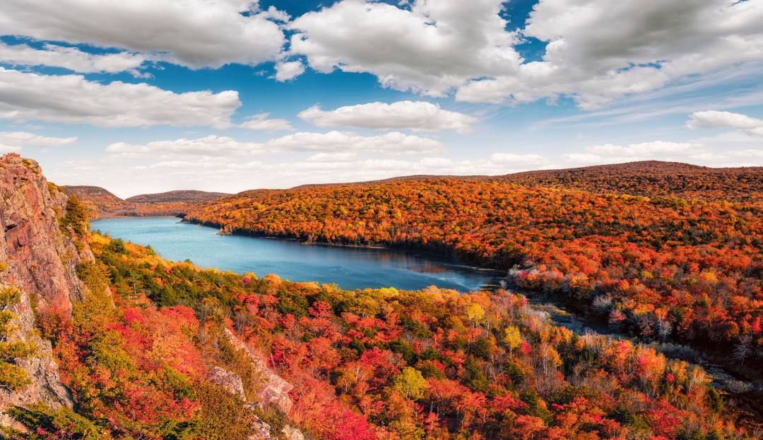 Autumn foliage surrounds a winding river valley with vibrant red and orange colors.