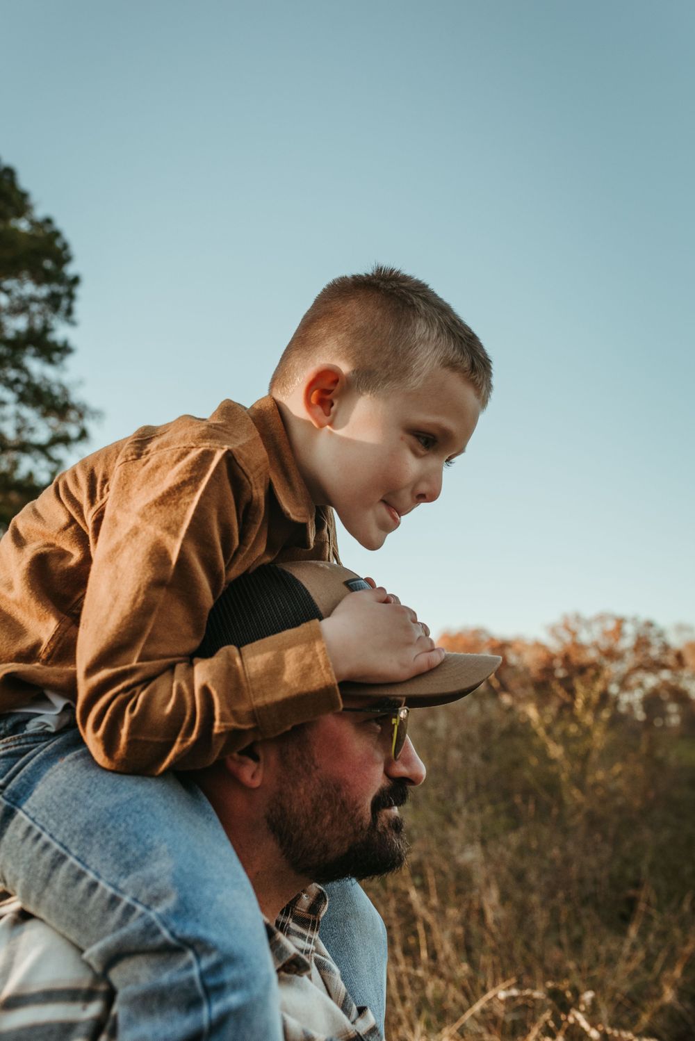 A child rides on shoulders while exploring the outdoors on a sunny day.