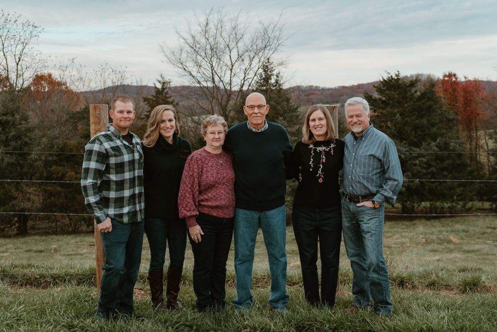 Extended family group photo taken outdoors in a rustic country setting during autumn.