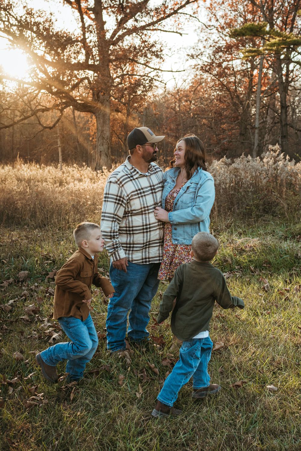 A happy family enjoying a playful moment in a golden autumn field at sunset.