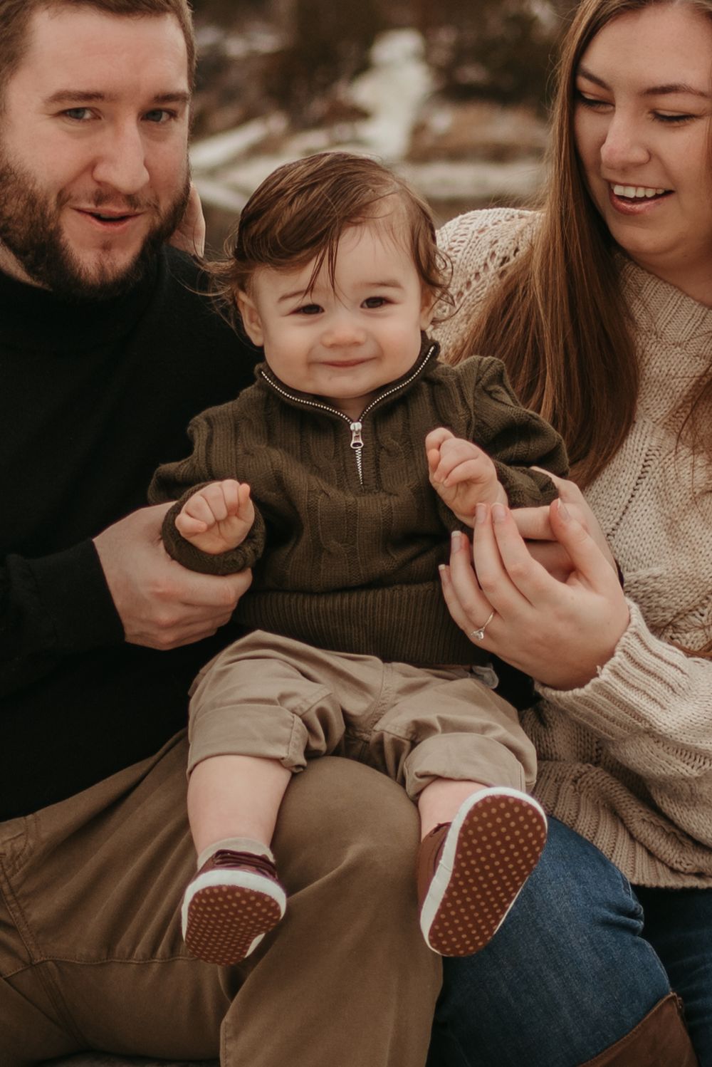 Happy family with toddler sitting together in cozy sweaters sharing a tender moment.