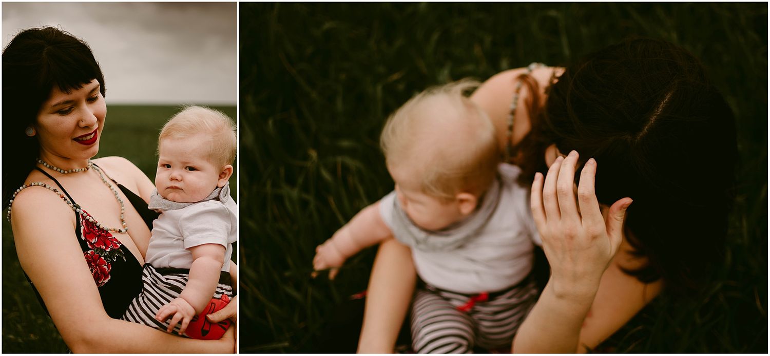 A baby in striped pants and light top sits with a caregiver in a floral dress outdoors during a summer day.