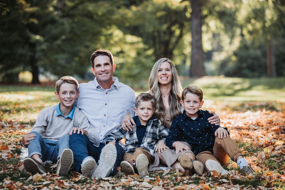 A family poses together in a colorful fall setting at Finch Arboretum, surrounded by vibrant autumn leaves.