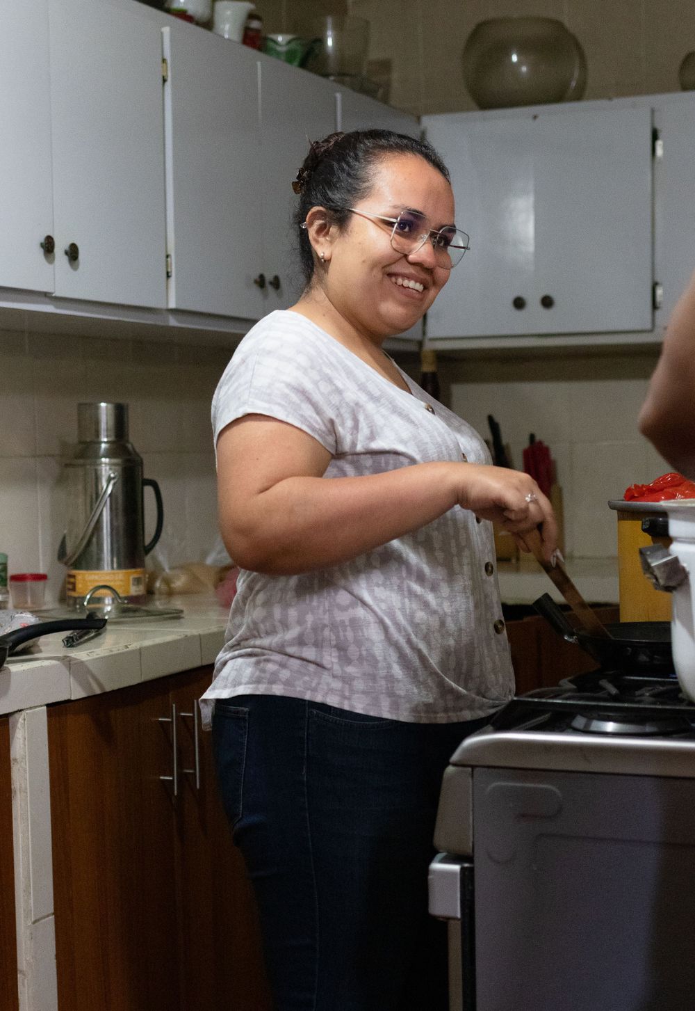 Someone cooking and preparing ingredients in a home kitchen with white cabinets.