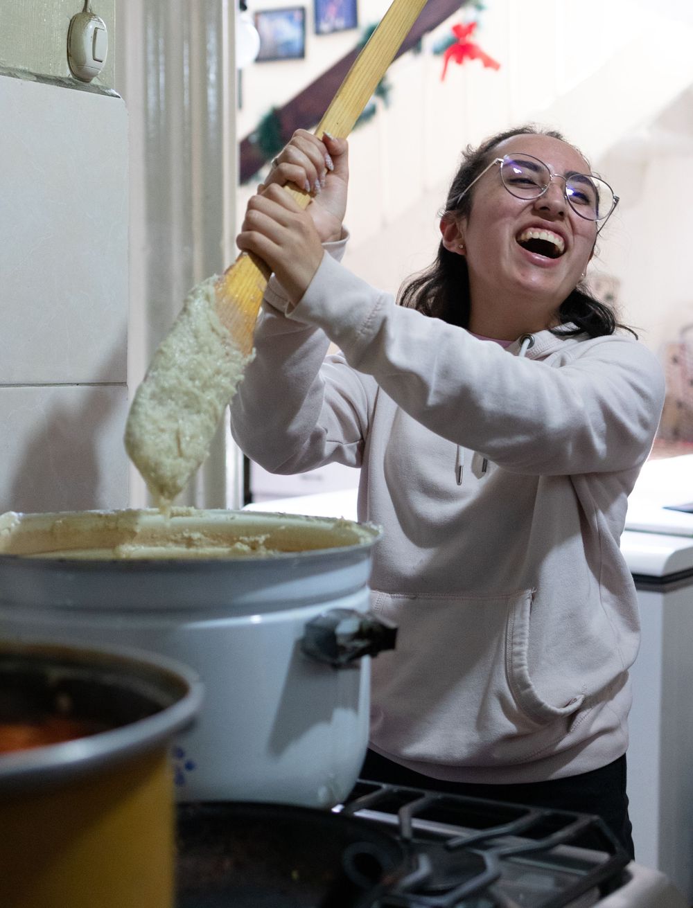 Someone joyfully cooking and stirring food in a kitchen while wearing a light colored sweatshirt.