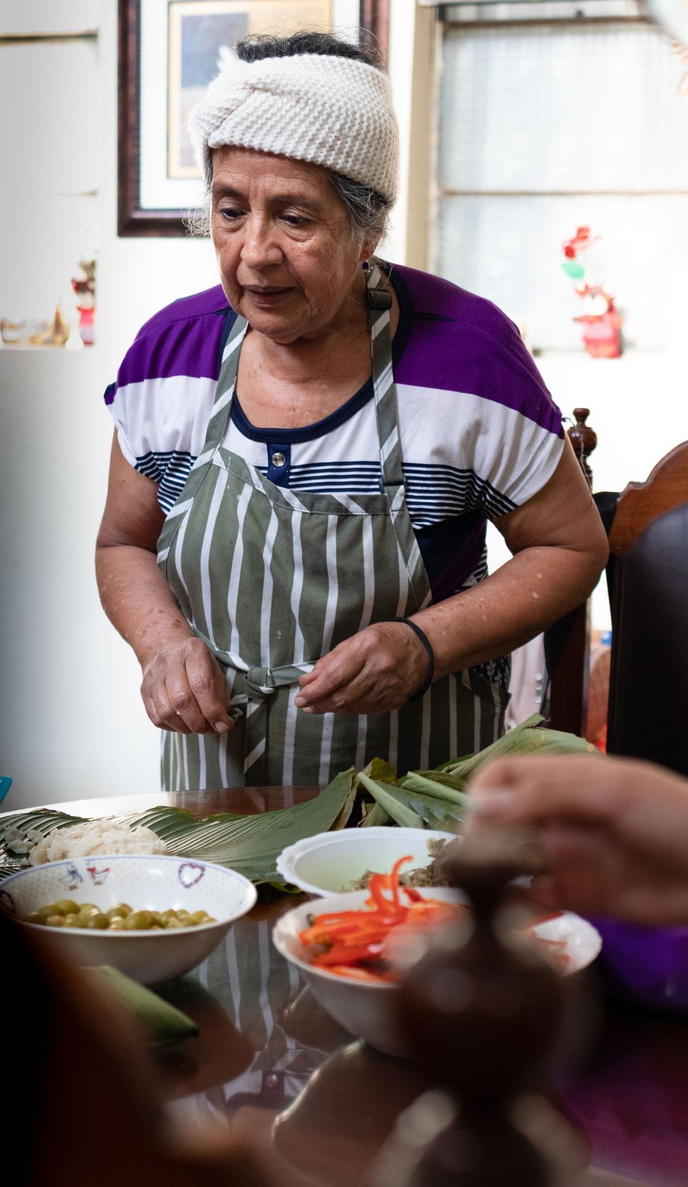 People in aprons preparing food at indoor gathering with traditional ingredients.