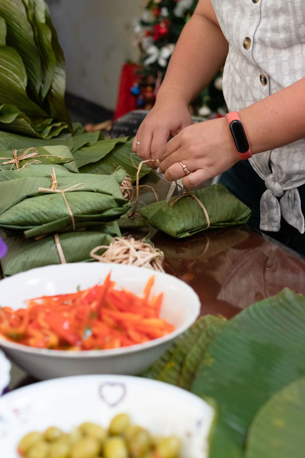 Hands preparing food ingredients on large green banana leaves.