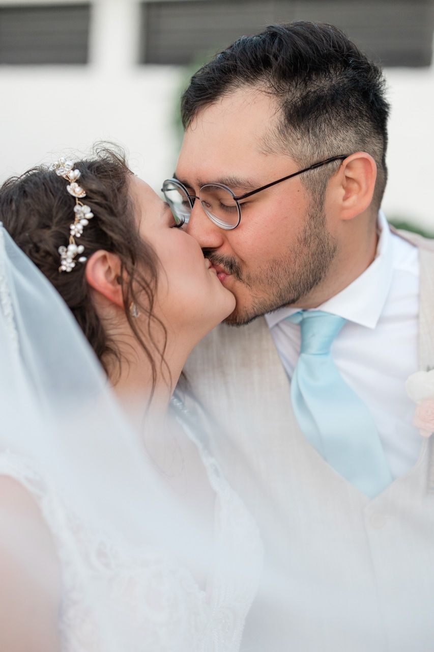Romantic wedding couple sharing intimate moment under veil.