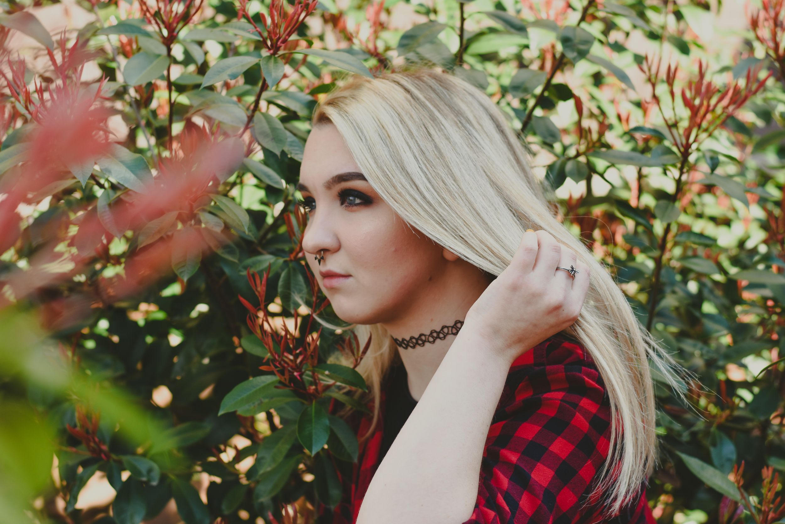 A young woman playing with her long, blonde hair amongst greenery