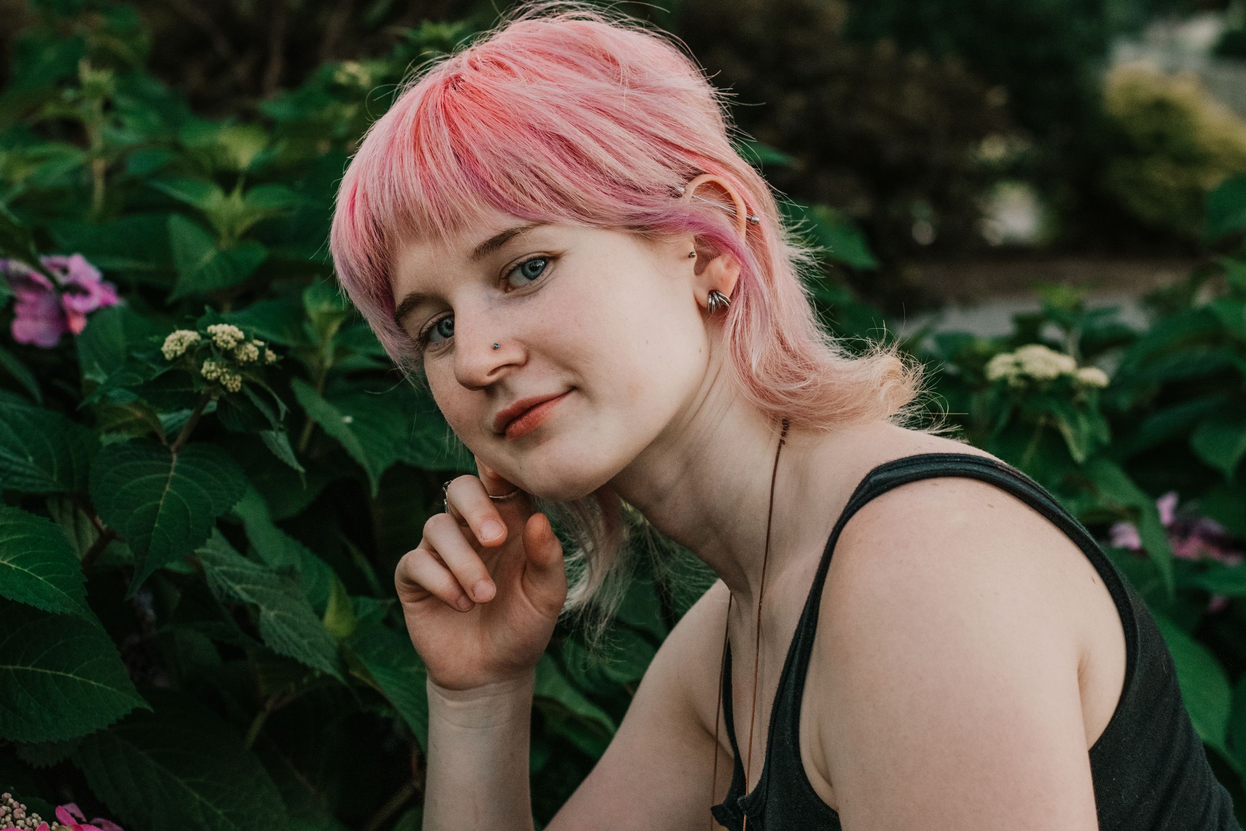 A young woman shares a knowing glance with the camera amidst lush greenery