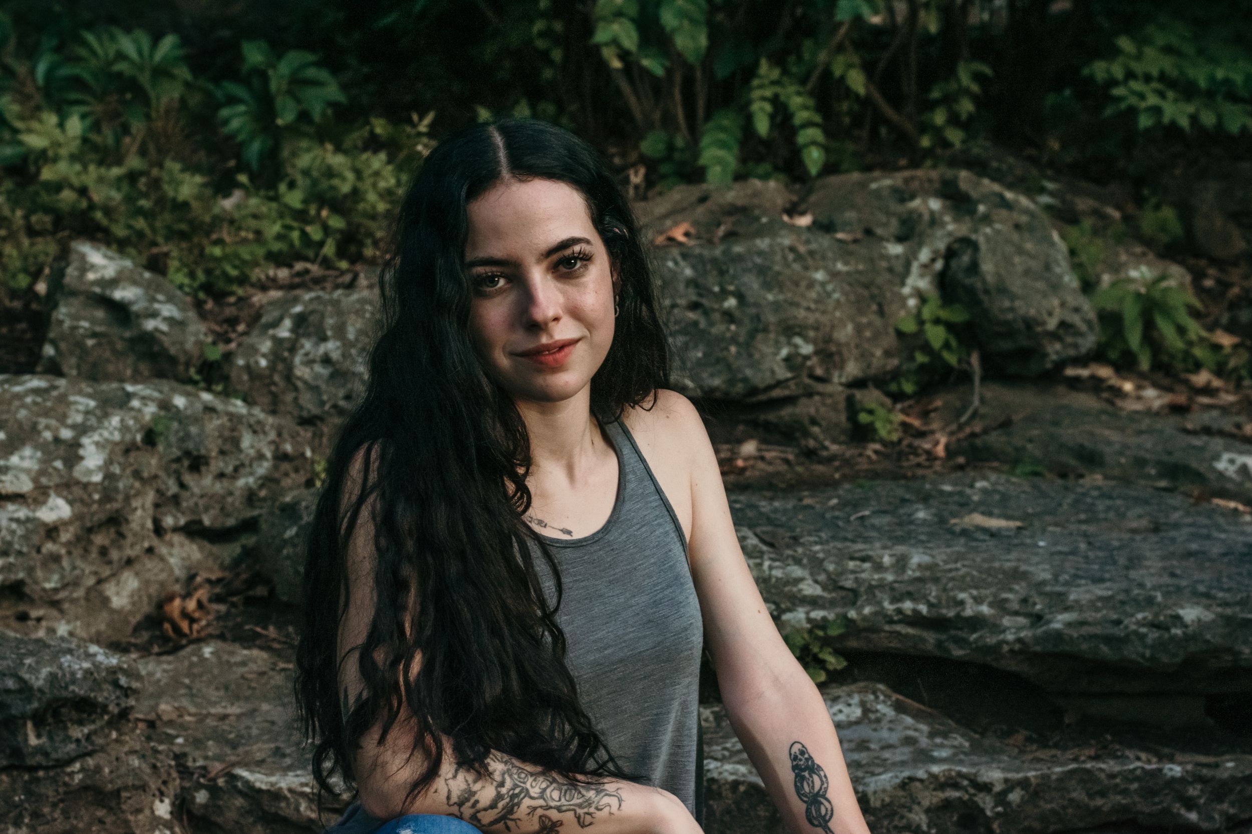 A young woman poses by a babbling brook at sundown