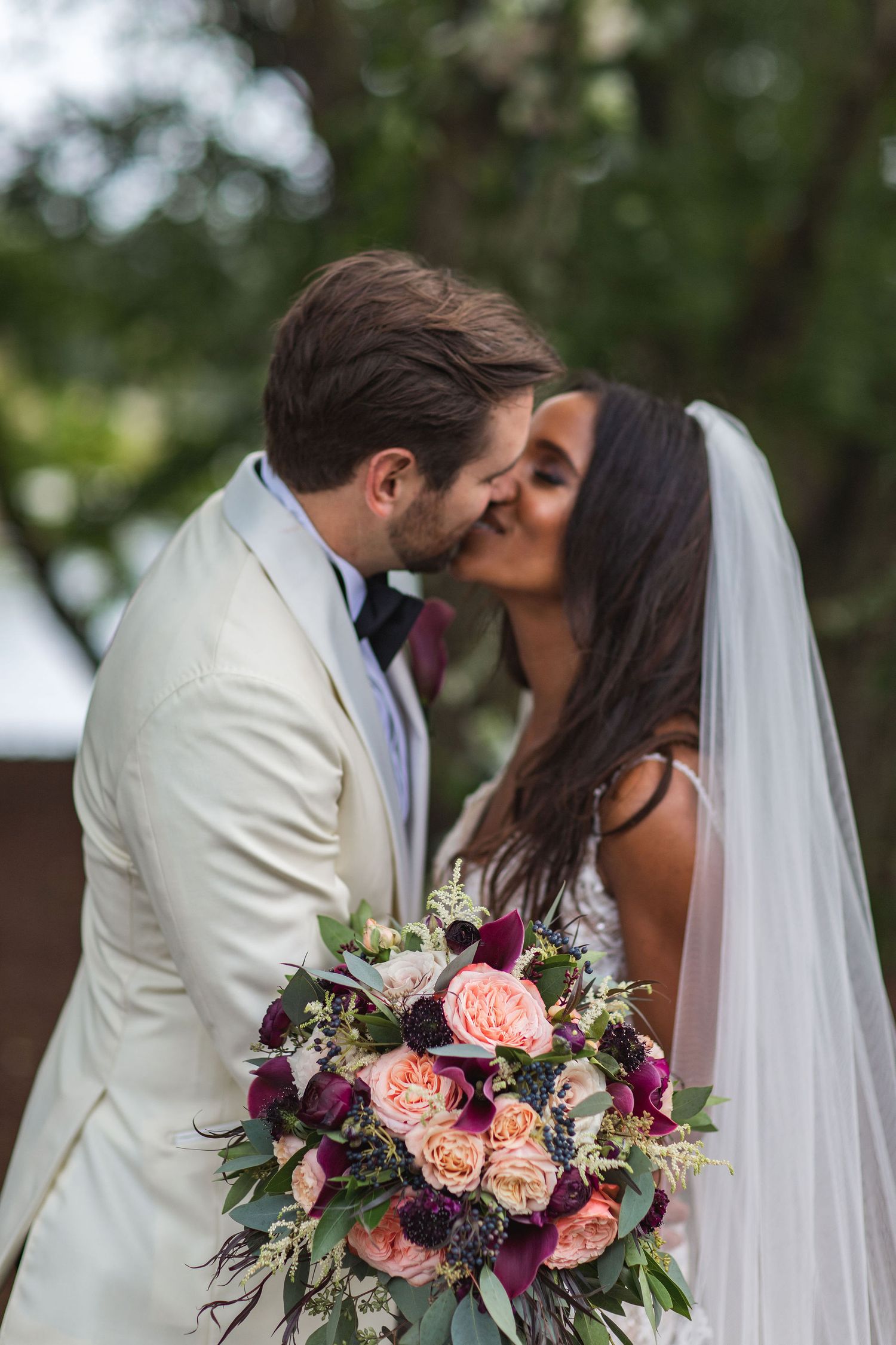 A romantic wedding moment captured with a vibrant floral bouquet featuring pink and purple blooms.