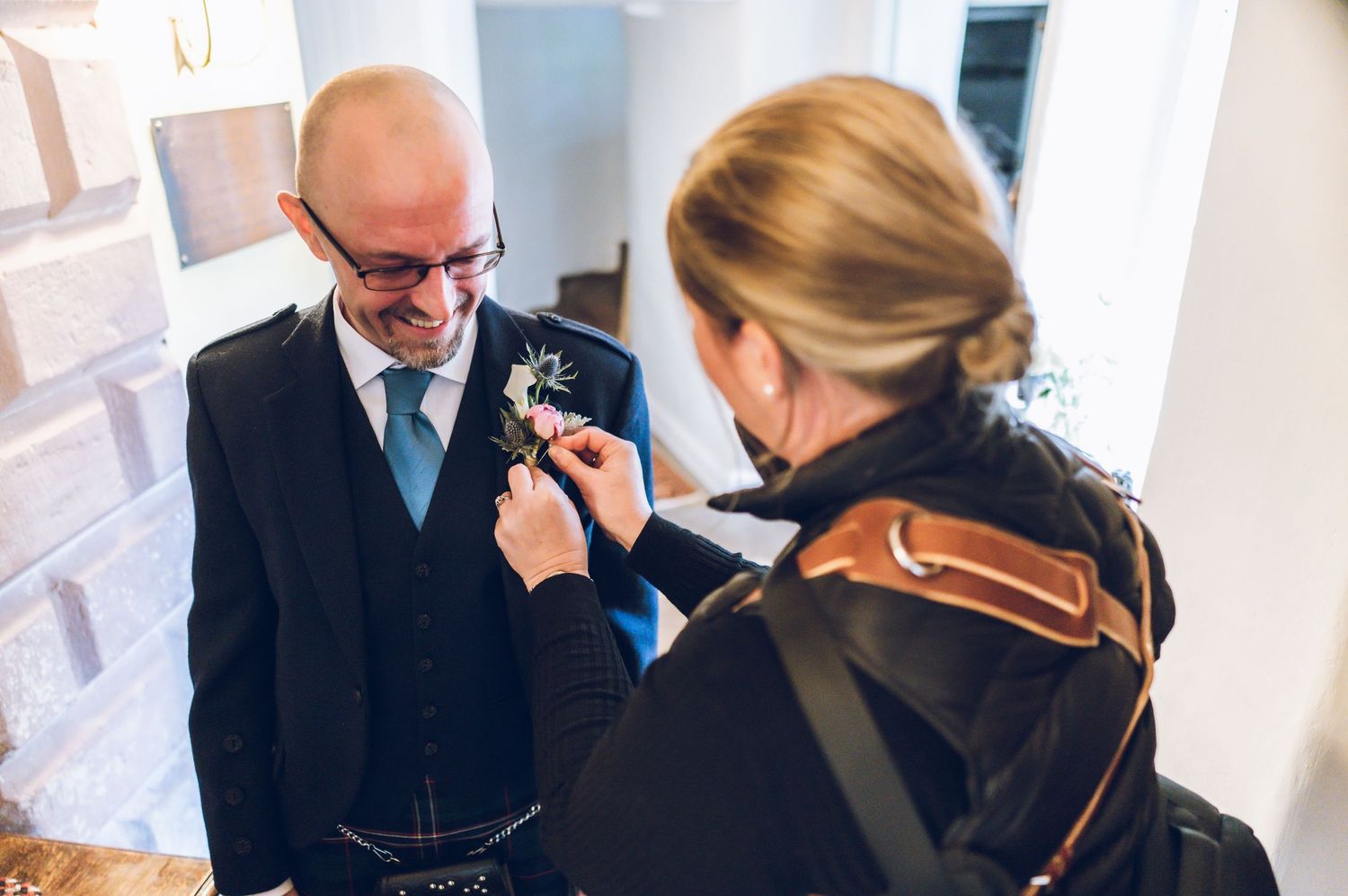 Wedding preparation scene showing boutonniere being pinned on groom's lapel.