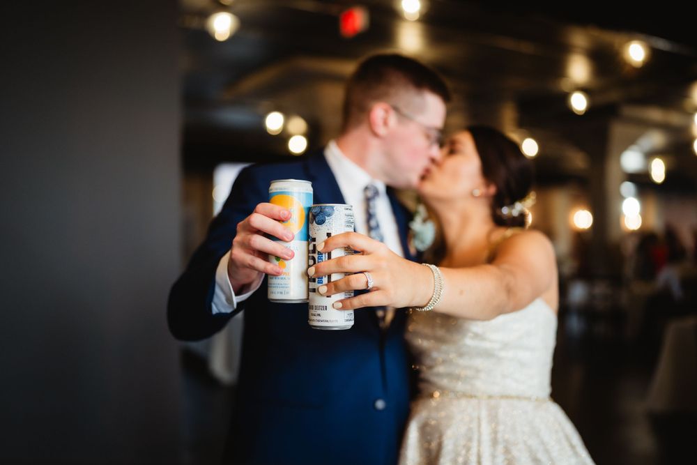 A couple shares a romantic moment while toasting with drinks at their wedding reception.