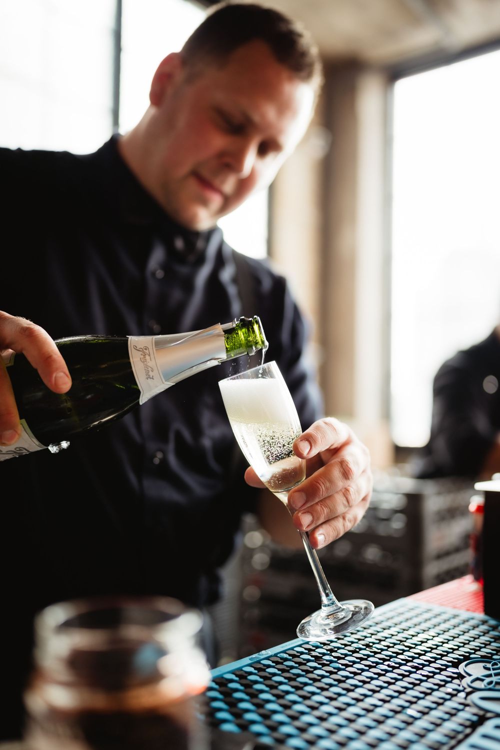 Bartender pouring champagne into a glass at an elegant event.