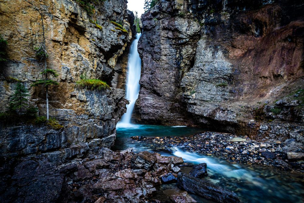 Dramatic waterfall plunging between tall rocky cliffs into a turquoise pool below.