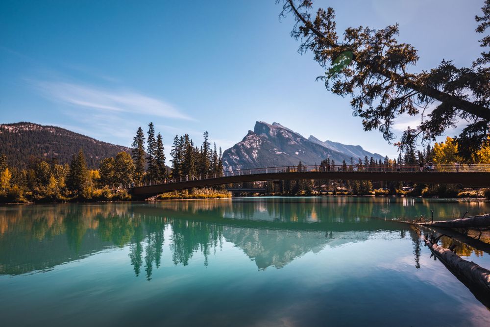 Calm mountain lake with perfect reflection of Mount Rundle and pine trees in Banff National Park.