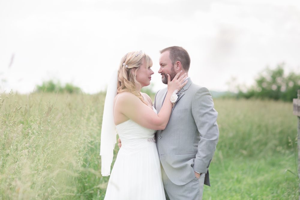 Tender moment between newlyweds in a sunlit meadow setting.